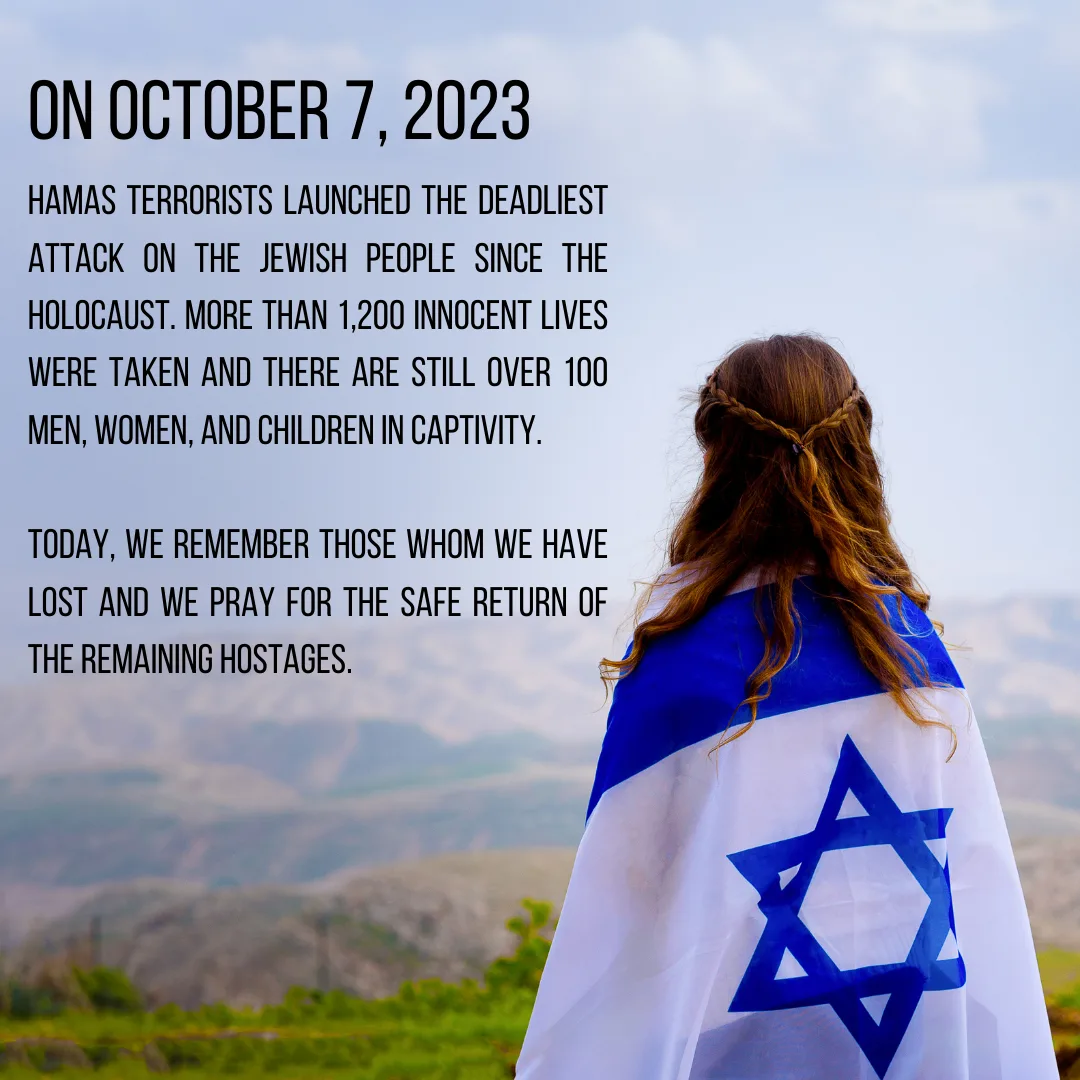 On October 7, 2023, Hamas terrorists launched the deadliest attack on the Jewish people since the Holocaust. More than 1,200 innocent lives were taken and there are still over 100 men, women, and children in captivity. Today, we remember those whom we have lost and we pray for the safe return of the remaining hostages. A young woman wrapped in an Israeli flag looks out over green hills.